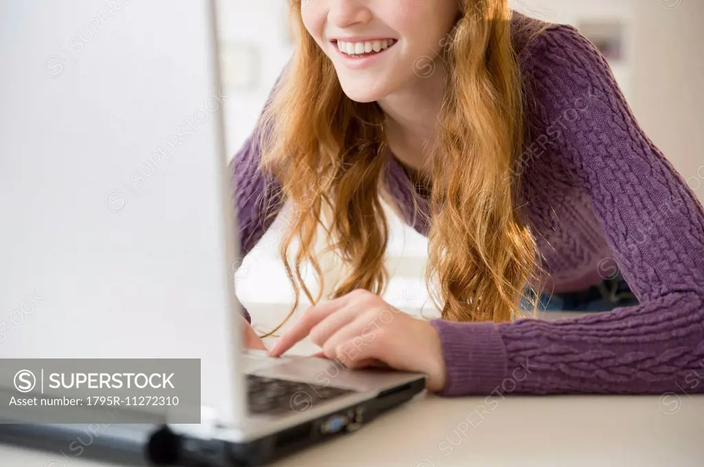 Girl (12-13) using laptop, mid section