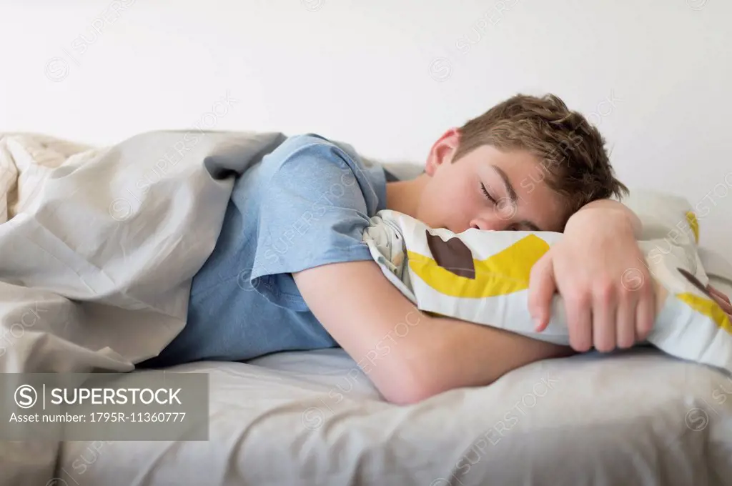 Teenage boy (16-17) sleeping in bed