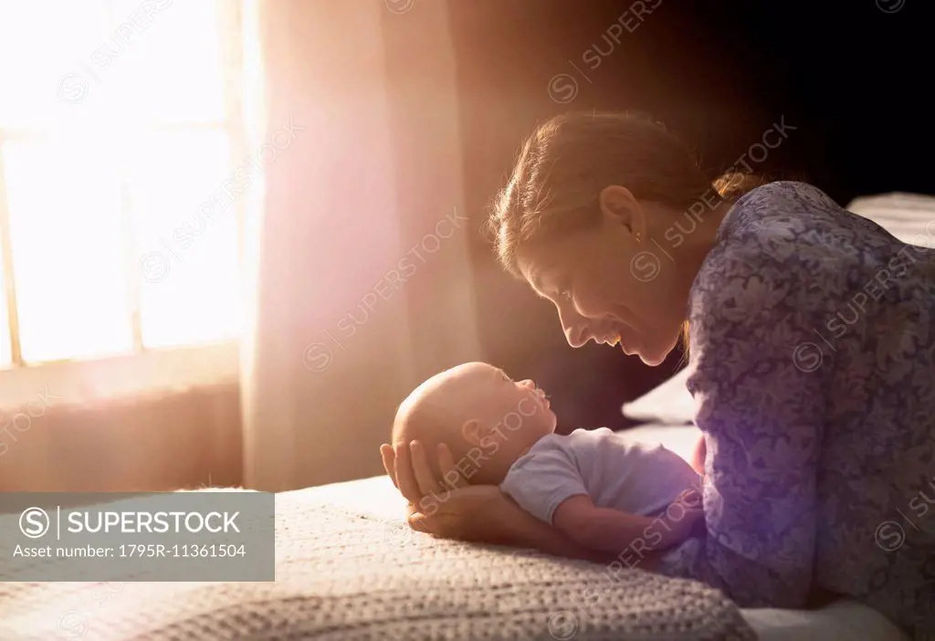 Mother holding baby boy (2-5 months) in bedroom