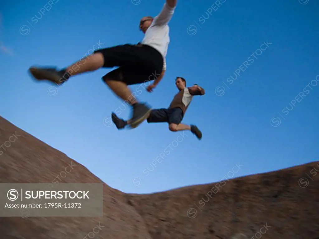 Men jumping over rock formations