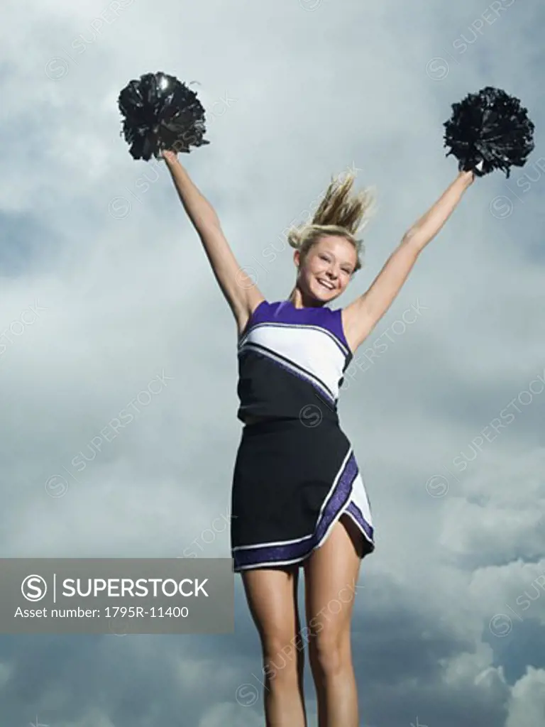 Cheerleader with pom poms jumping