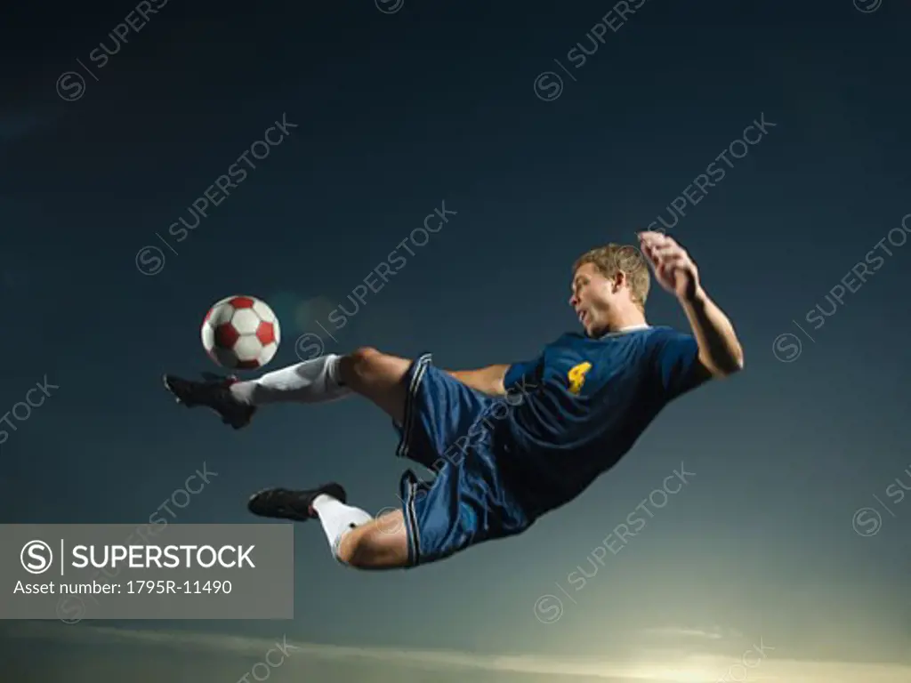Man kicking soccer ball in air