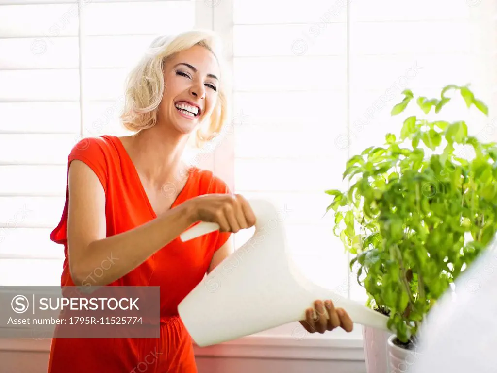 Woman in red dress watering potted plant