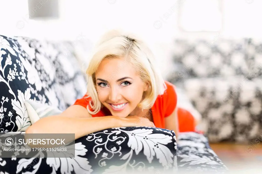 Close-up of woman lying down on sofa and smiling to camera