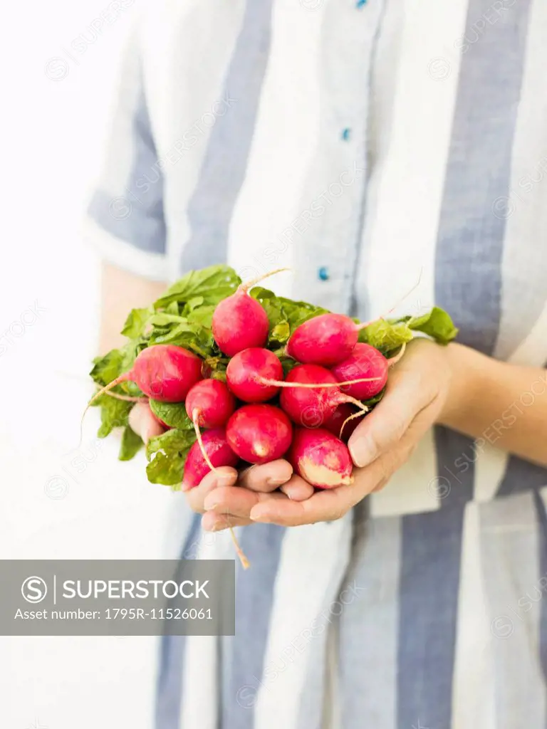 Studio shot of woman holding bunch of fresh radishes