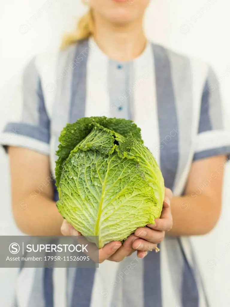 Studio shot of woman holding fresh cabbage