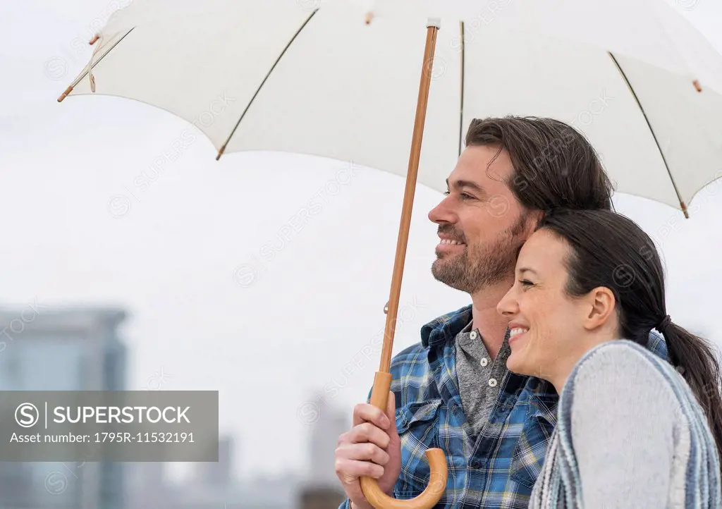 Side view of couple under umbrella