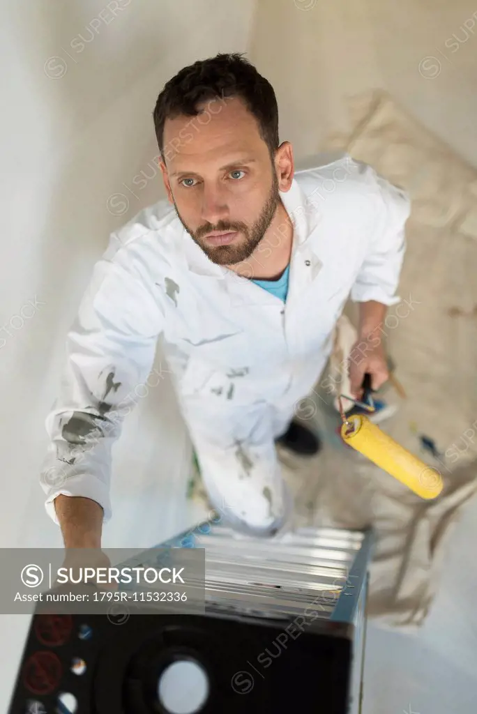 Man climbing ladder with paint roller