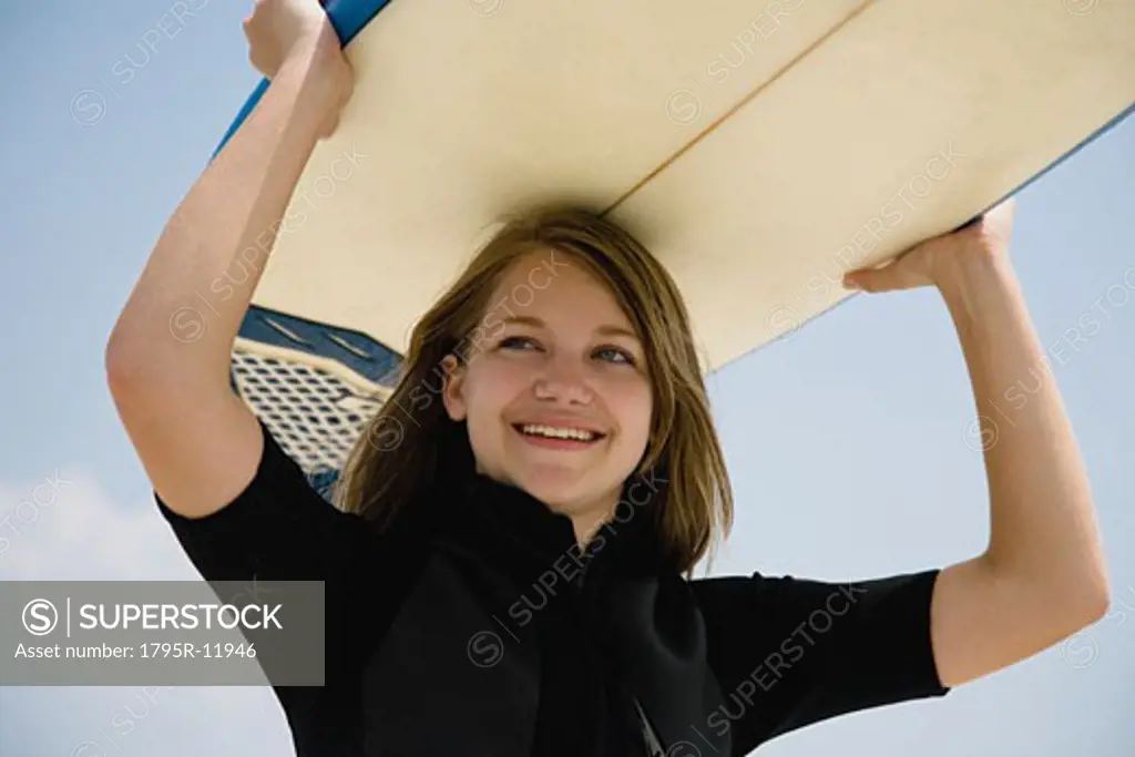 Girl holding surfboard on head, Florida, United States
