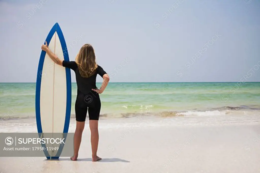 Girl holding surfboard in sand, Florida, United States