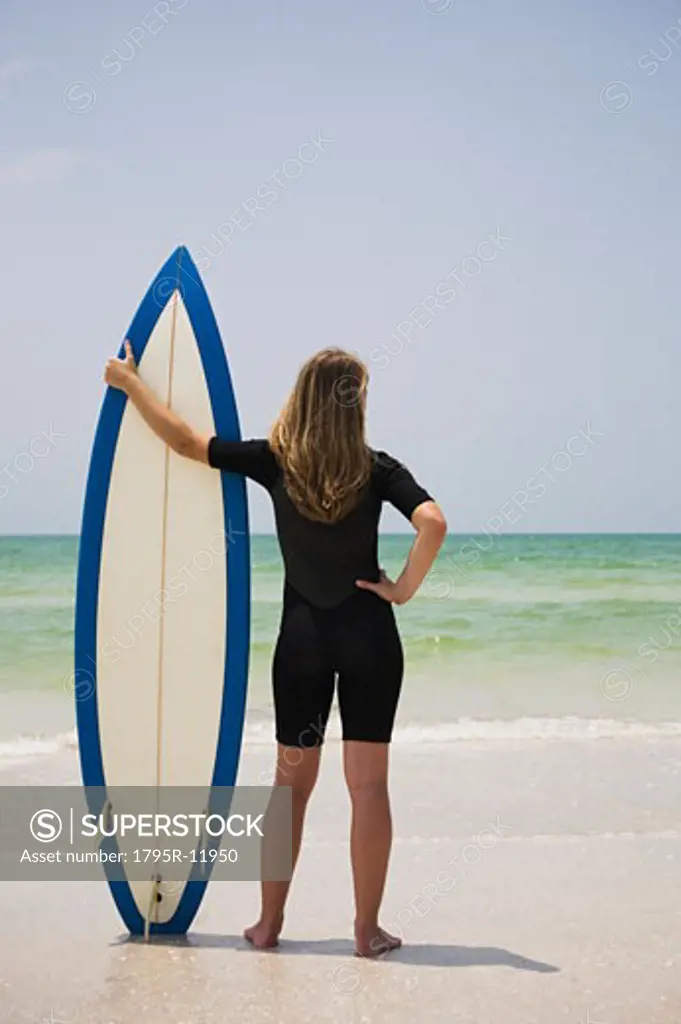 Girl holding surfboard in sand, Florida, United States
