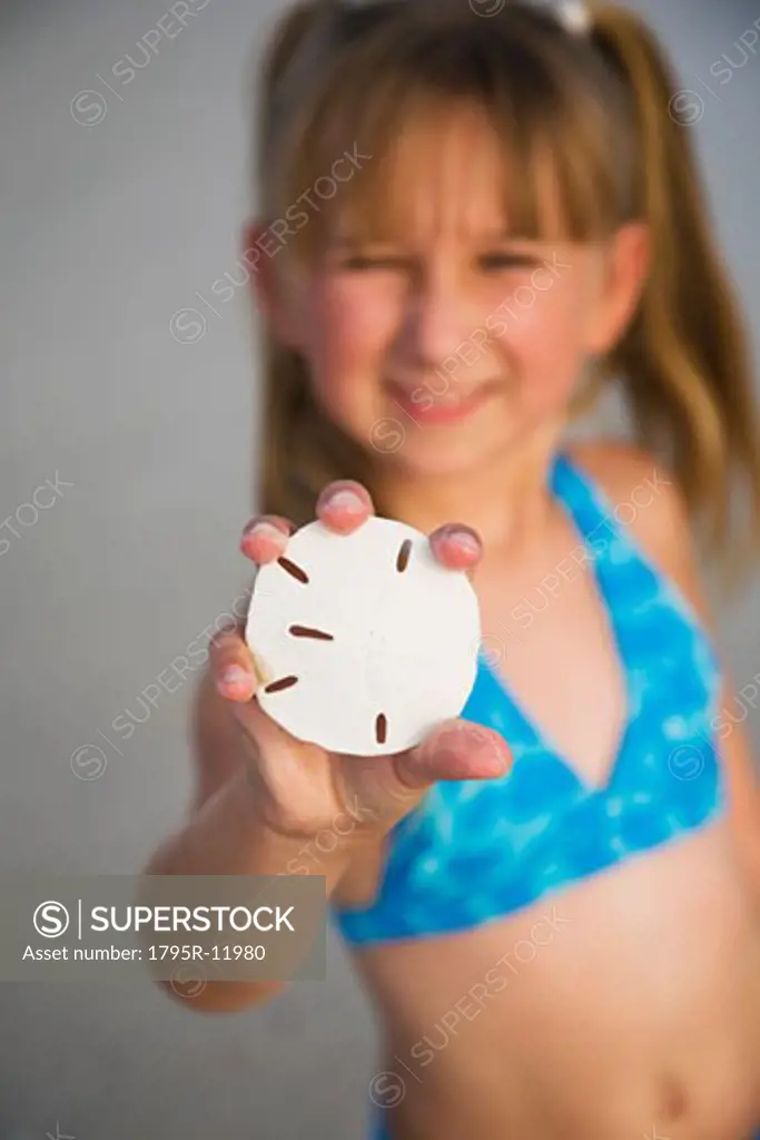Girl holding up sand dollar, Florida, United States