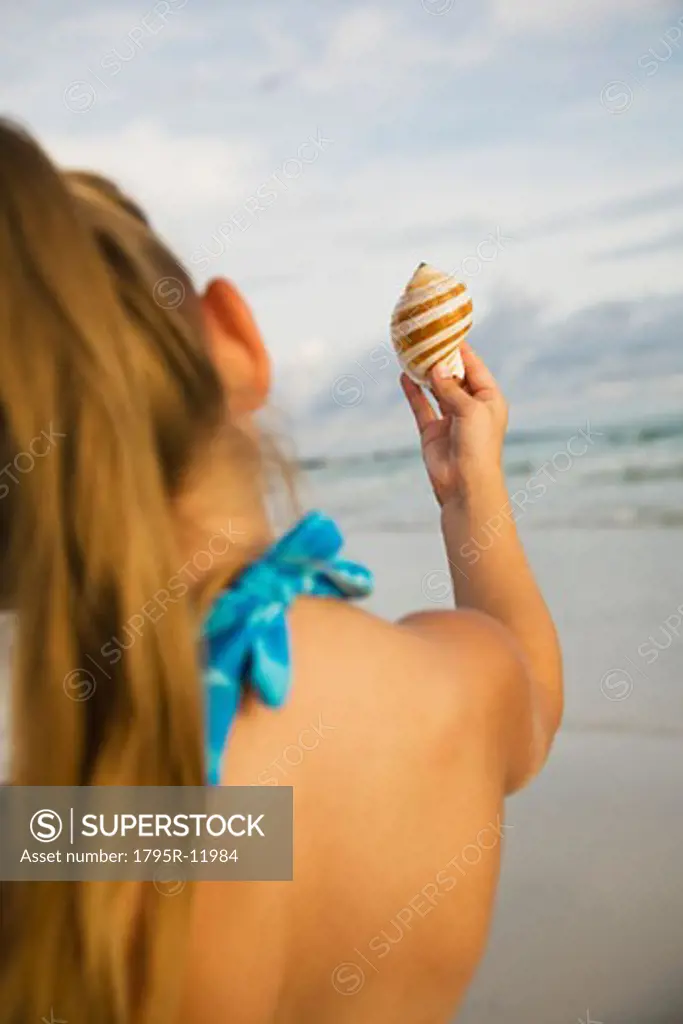 Girl holding up sea shell, Florida, United States