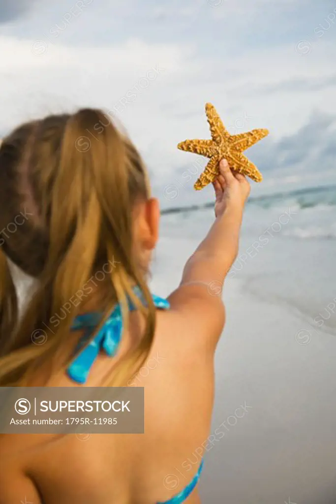Girl holding up starfish, Florida, United States