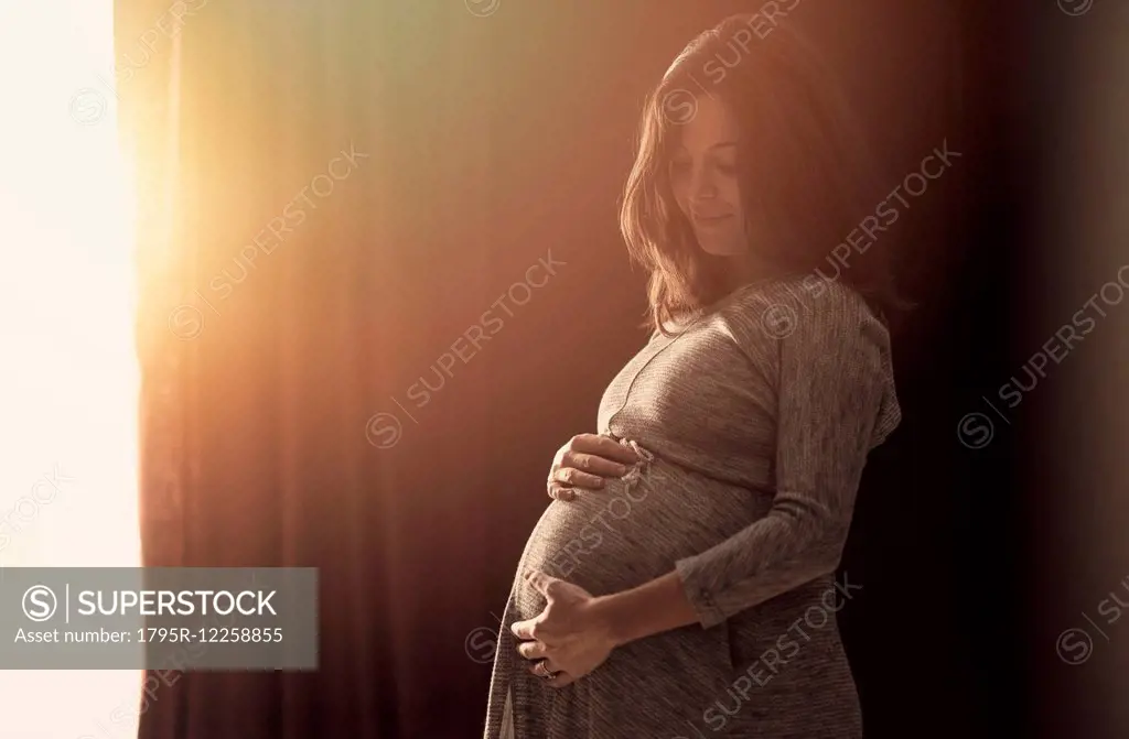 Pregnant woman touching belly at home