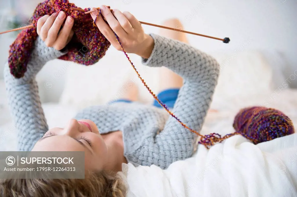 Young woman lying down and knitting