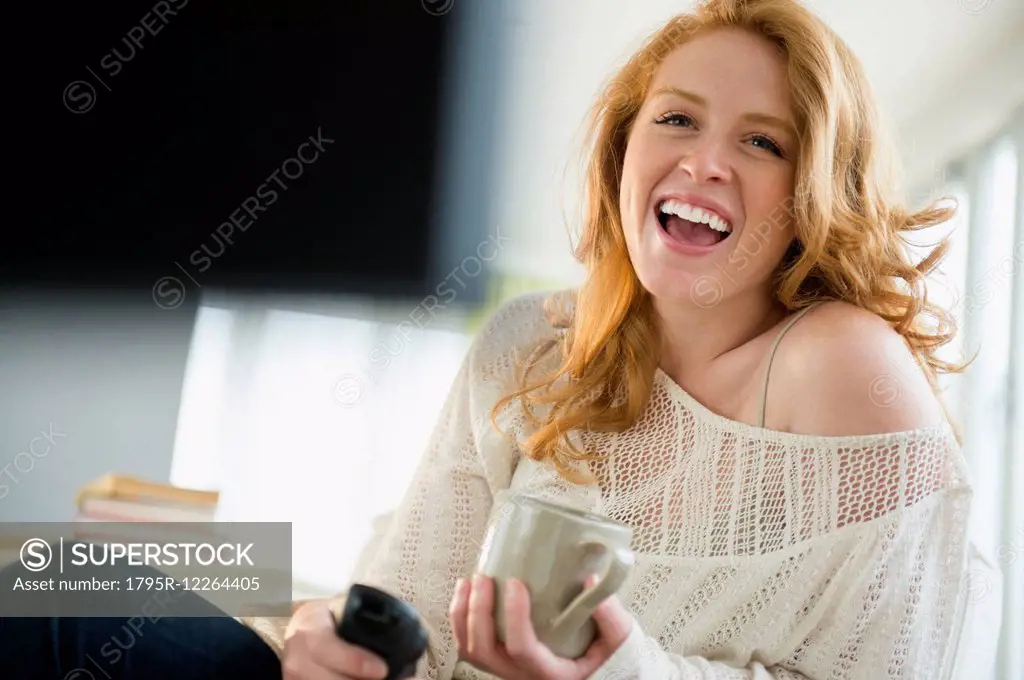 Young woman watching television and laughing