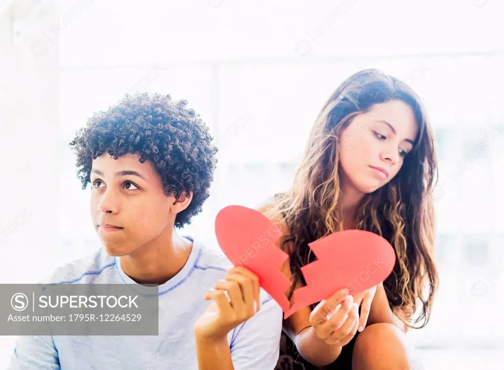 Portrait of young couple with broken heart made from paper