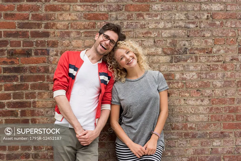 Portrait of couple standing against brick wall