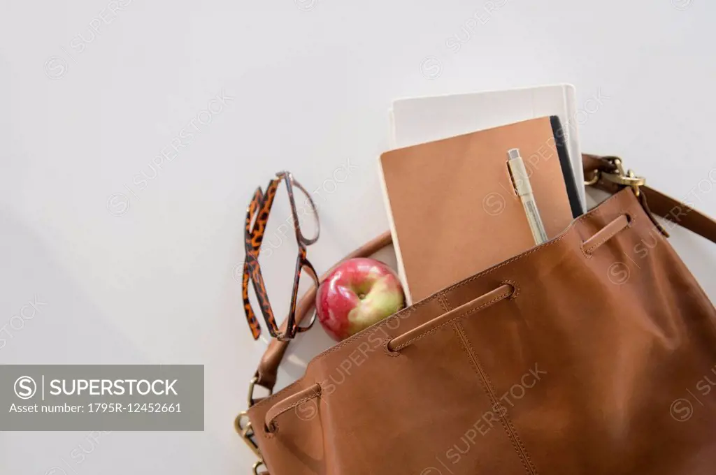 Studio Shot of shoulder bag with apple and notebook in it