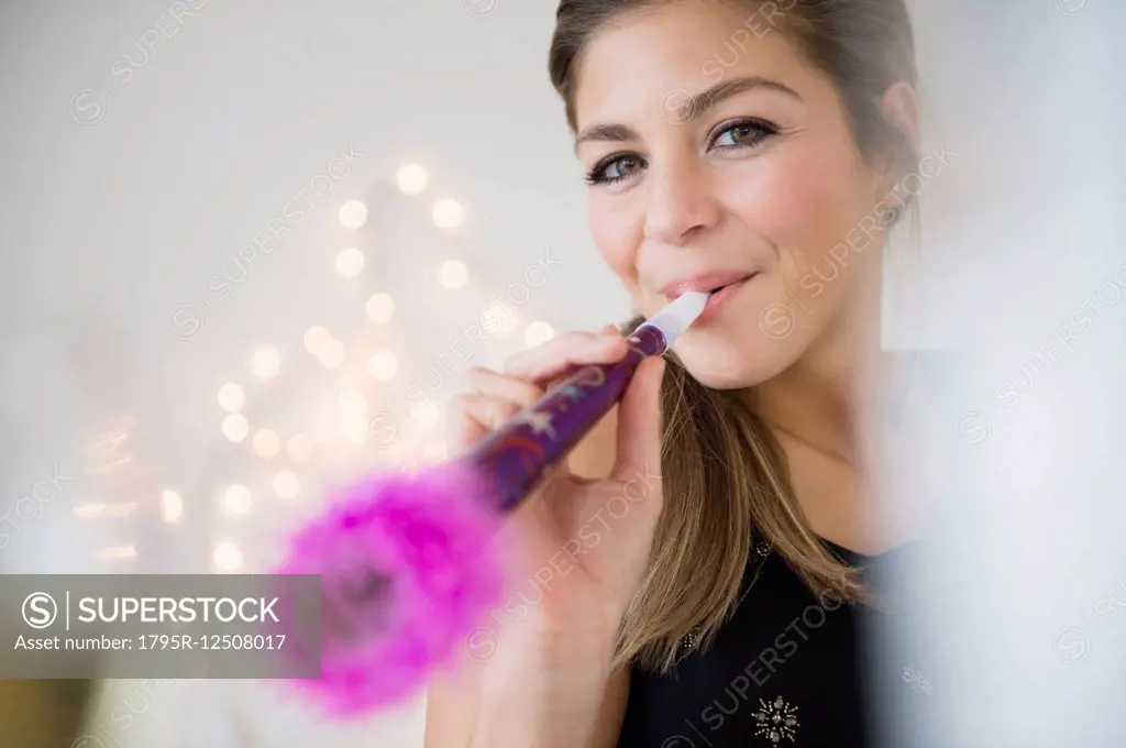 Young woman blowing noisemaker at party