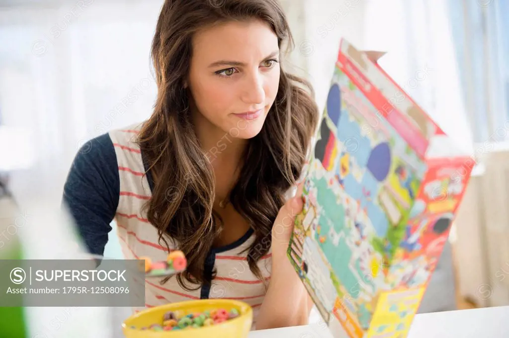 Woman eating cereal reading info on box