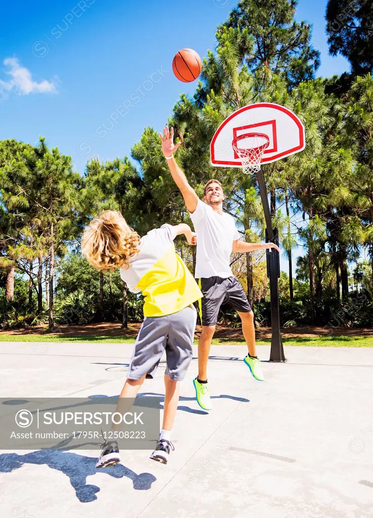 Boy (8-9) playing basketball with his brother