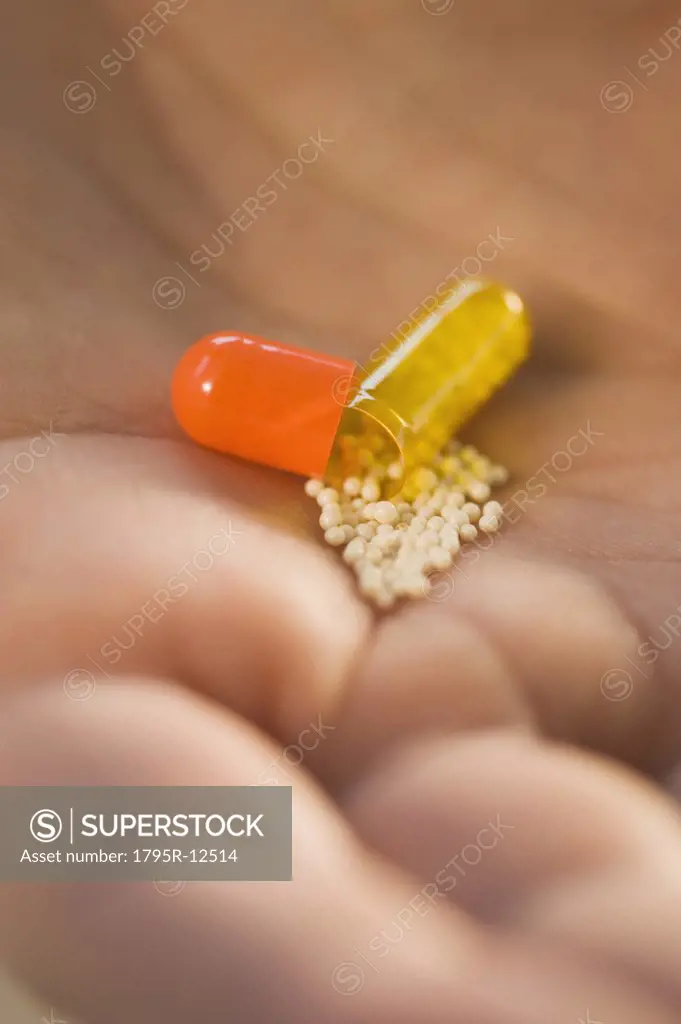 Close-up of open medication capsule in man's hand