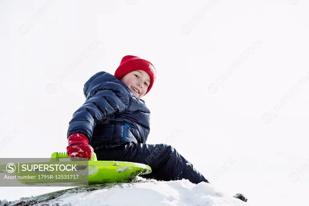 Boy (6-7) sledding in winter