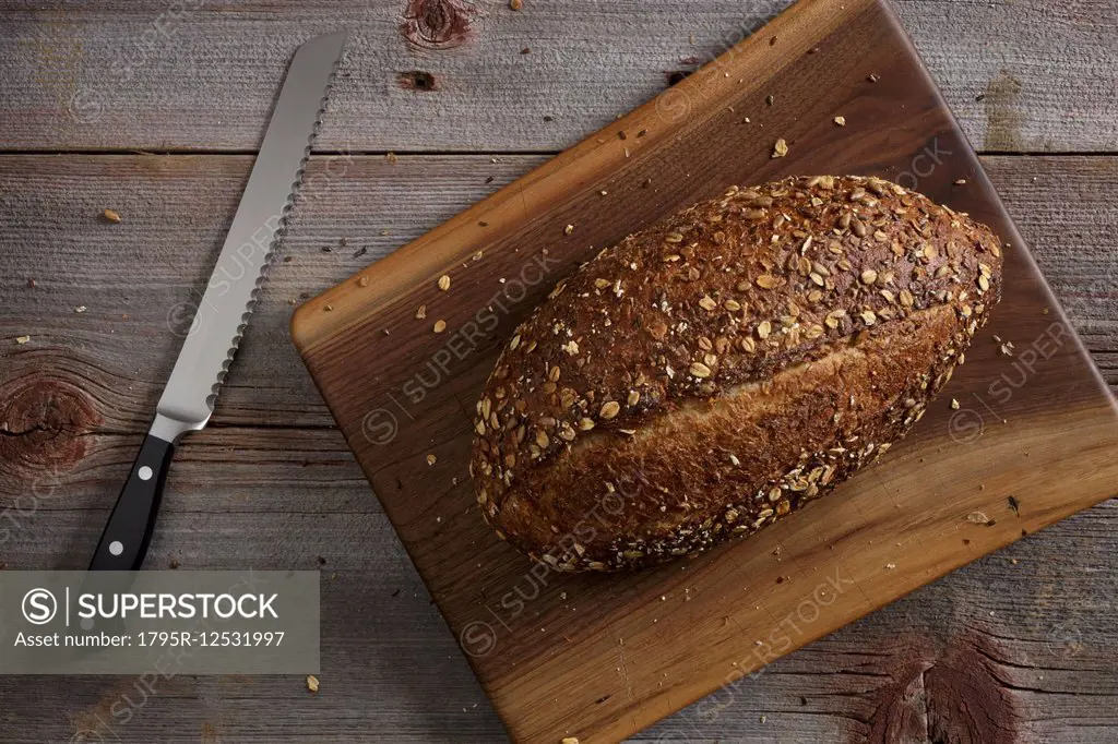 Kitchen knife and loaf of bread on wooden table