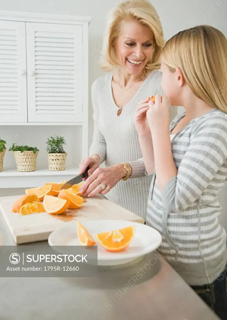 Grandmother and granddaughter cutting oranges