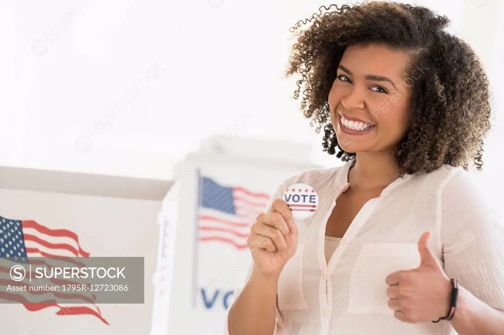 Young woman holding voting badge and smiling