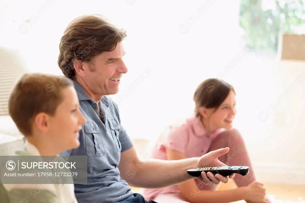 Children (8-9, 10-11) watching TV with their father