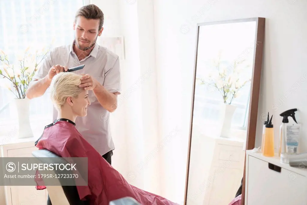Hairdresser combing woman's hair