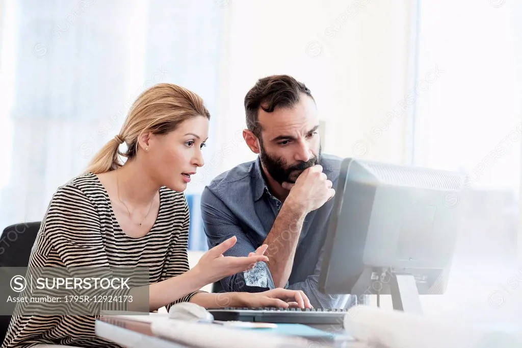 Man and woman looking at computer in office