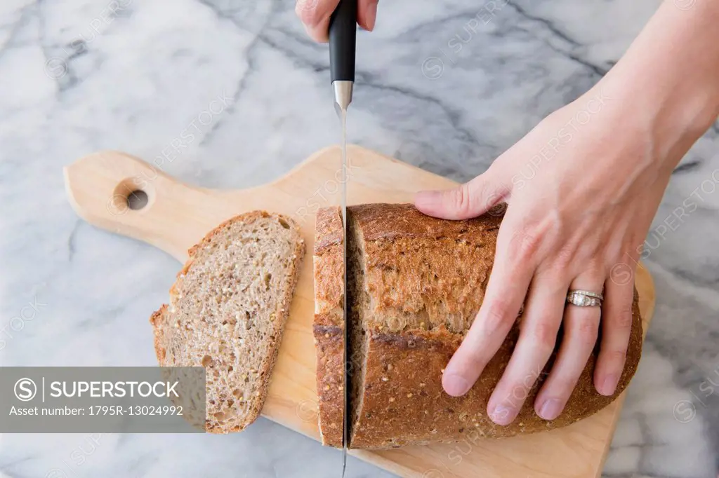 Close-up of woman's hands cutting bread