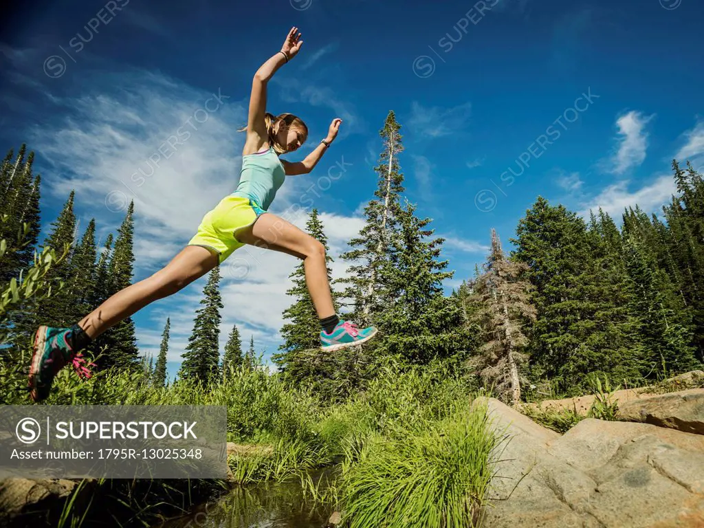 Teenage girl (14-15) jumping in forest