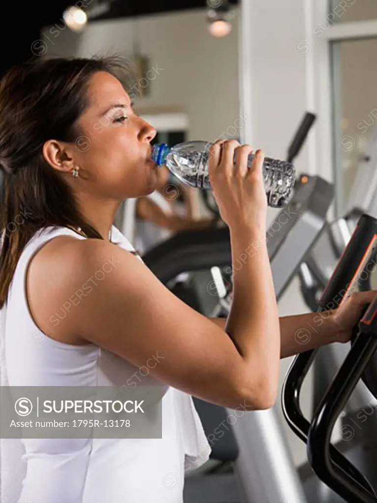 Woman drinking water on exercise machine