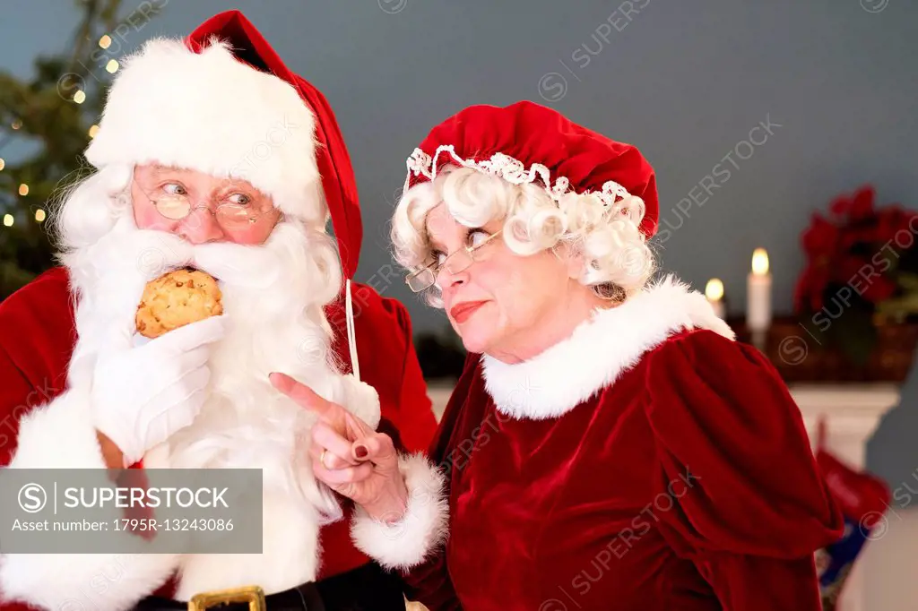 Mrs. Claus pointing on Santa eating gingerbread cookie