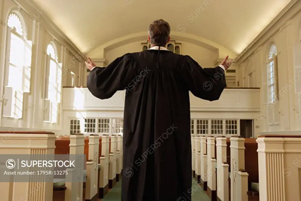 Priest with arms raised in church
