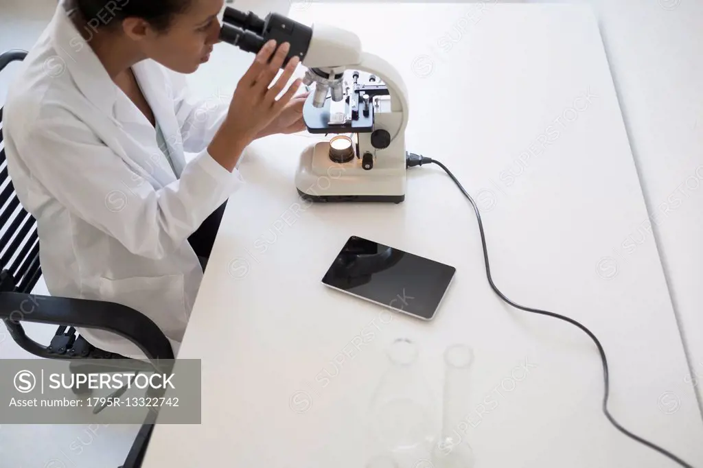 Woman scientist looking through microscope