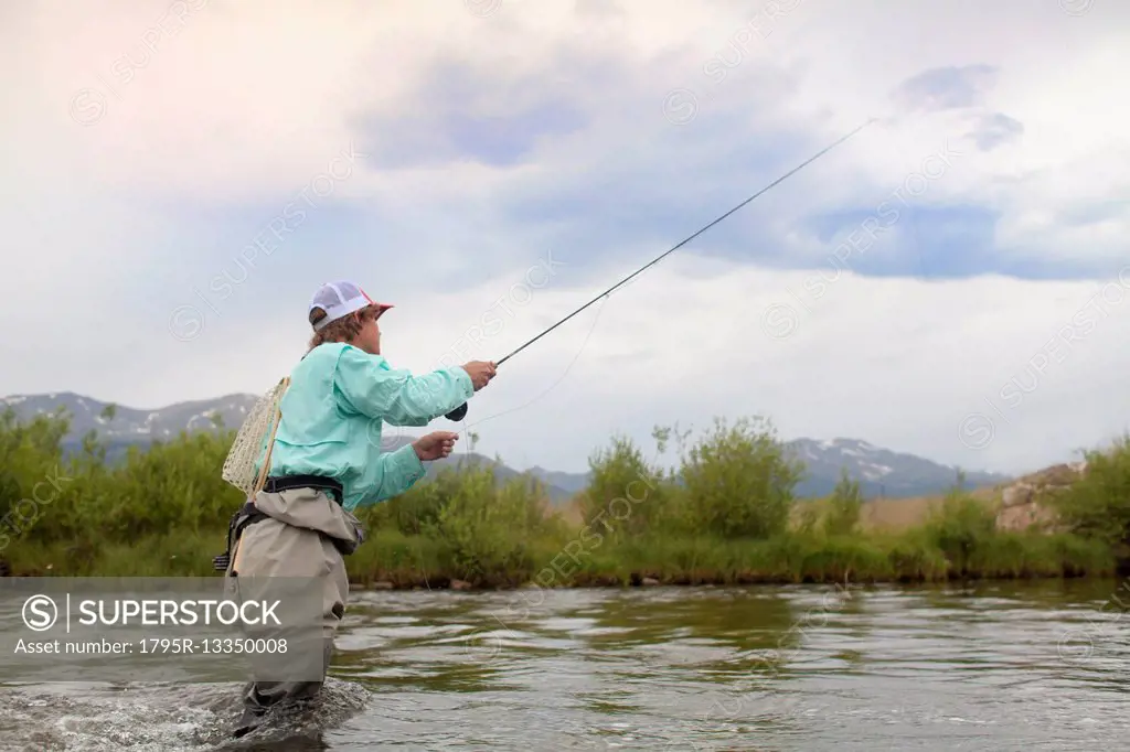Colorado, Mid adult man wading and fishing in river