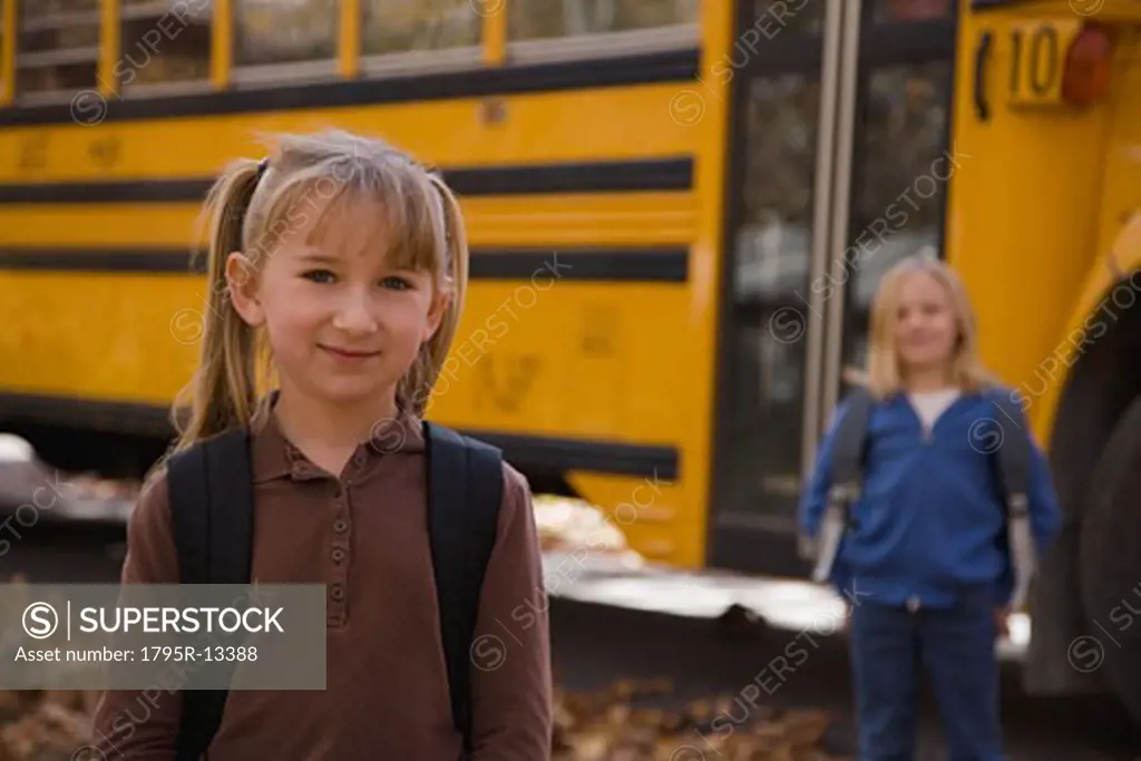 Girl with backpack in front of school bus