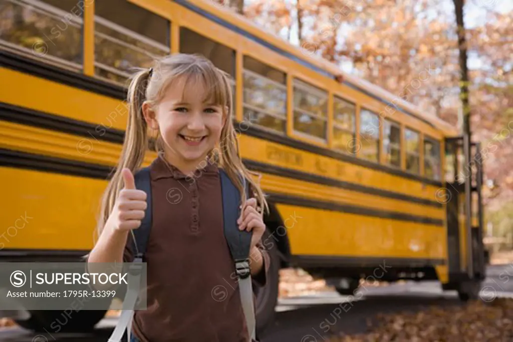 Girl with backpack in front of school bus
