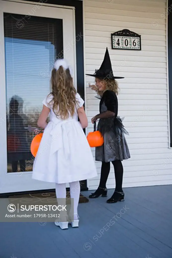 Girls in wtich and princess Halloween costumes trick or treating