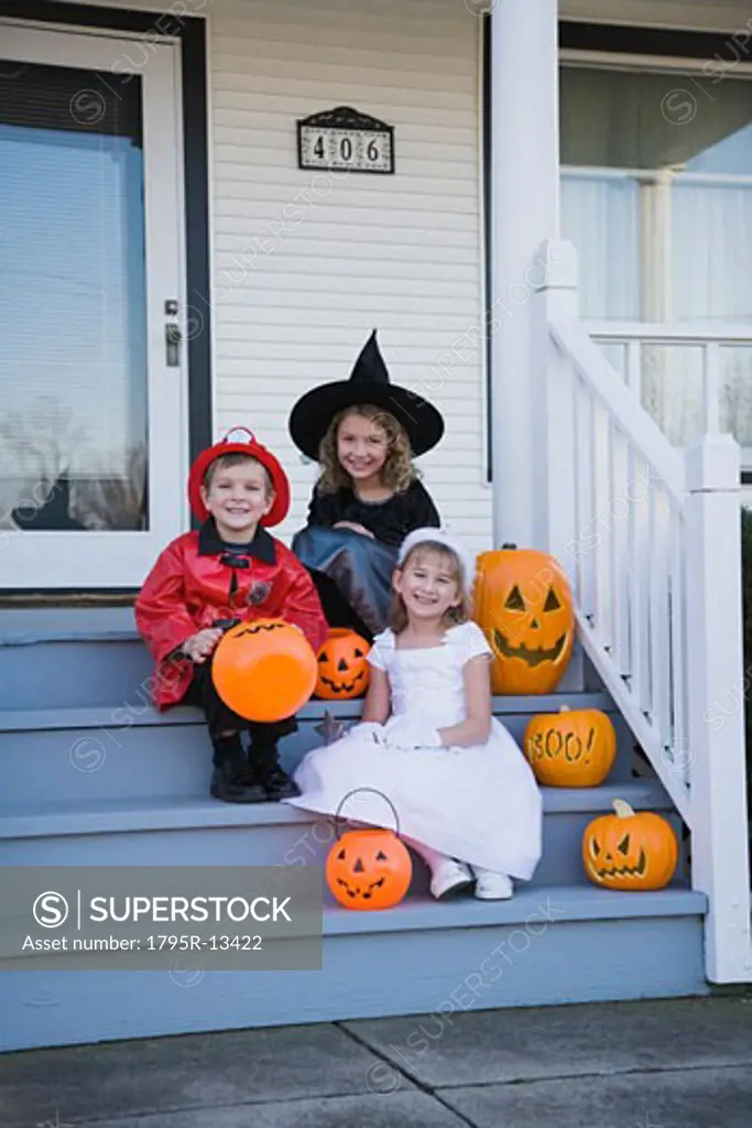 Children in Halloween costumes sitting on porch