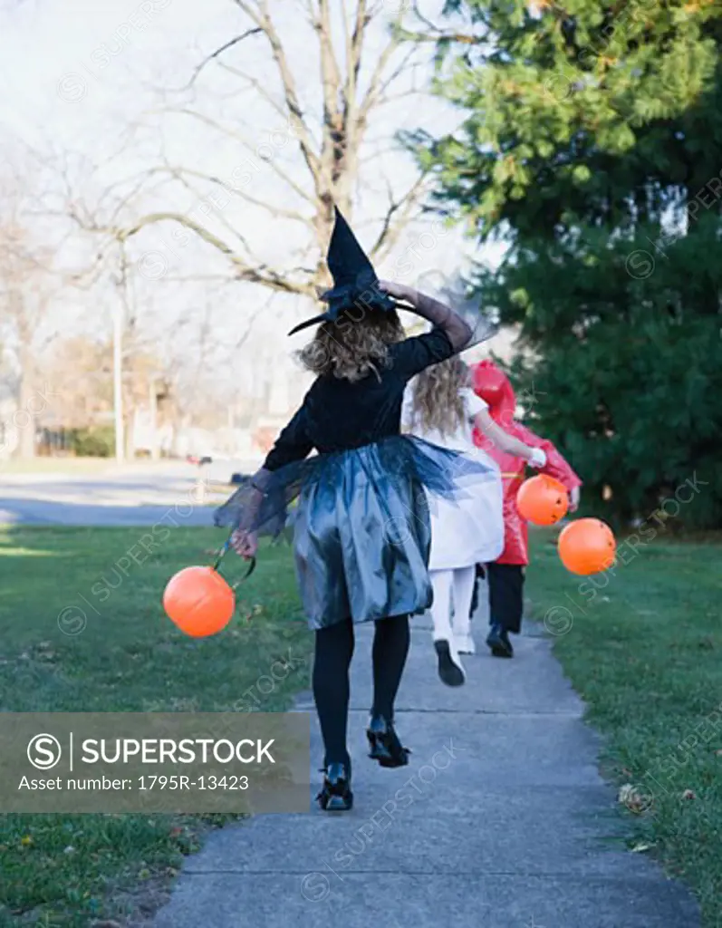 Children in Halloween costumes skipping on sidewalk