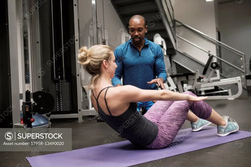 Woman exercising with personal trainer in gym