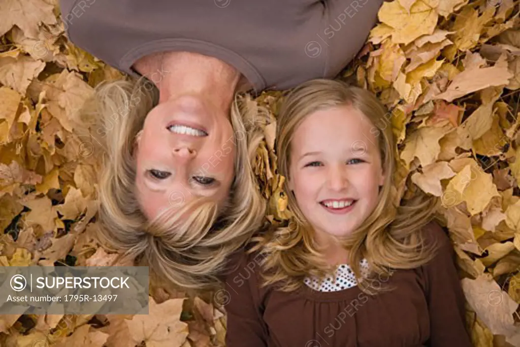 Mother and daughter laying in autumn leaves