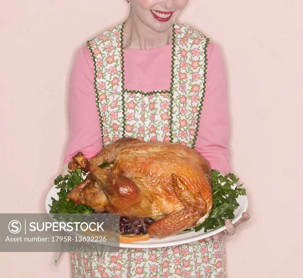 Smiling senior woman holding garnished turkey on plate